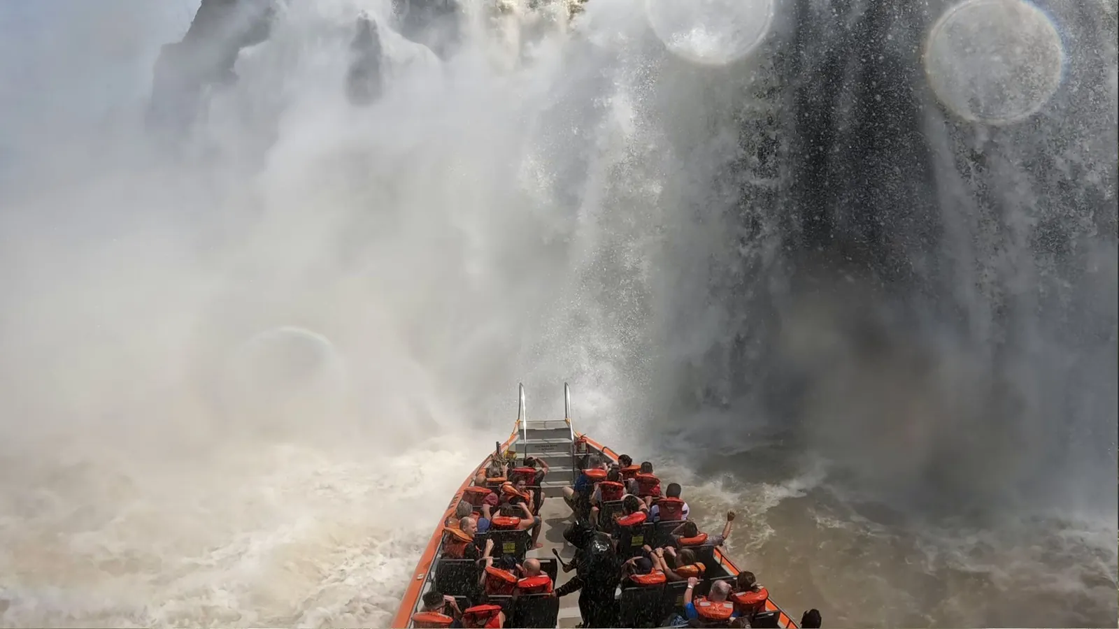 Gran Aventura speedboat full of passengers in life jackets heading into the thick spray at the foot of a waterfall, Iguazú Falls, Argentina