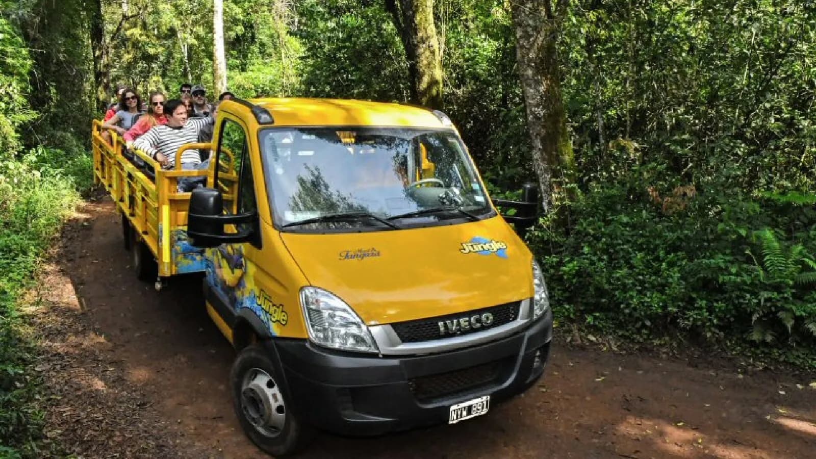 Open-sided yellow Iguazú Jungle truck carrying visitors along the dirt Yacaratiá trail through the subtropical rainforest