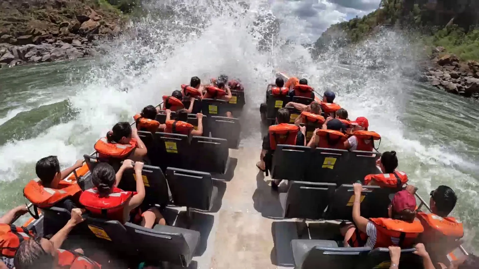Passengers in orange life jackets holding on as the Gran Aventura boat crashes through white-water rapids, sending up a wall of spray