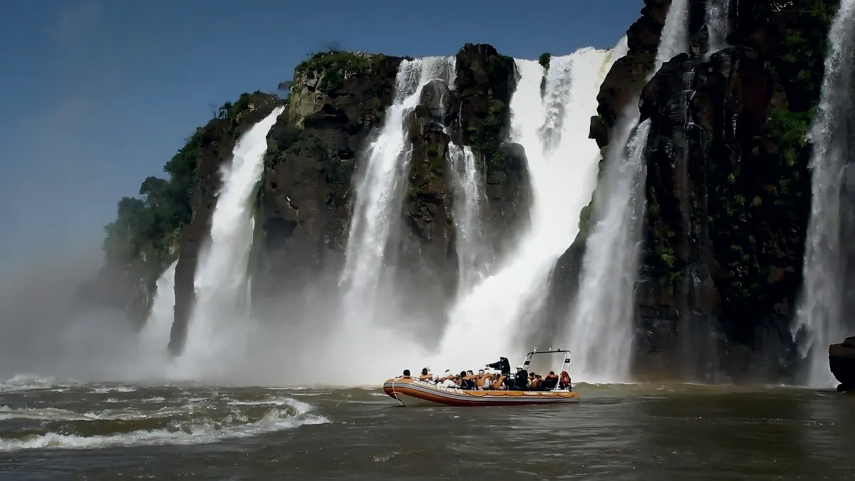 A Macuco Safari boat dwarfed by the wall of waterfalls it is approaching at Iguazu